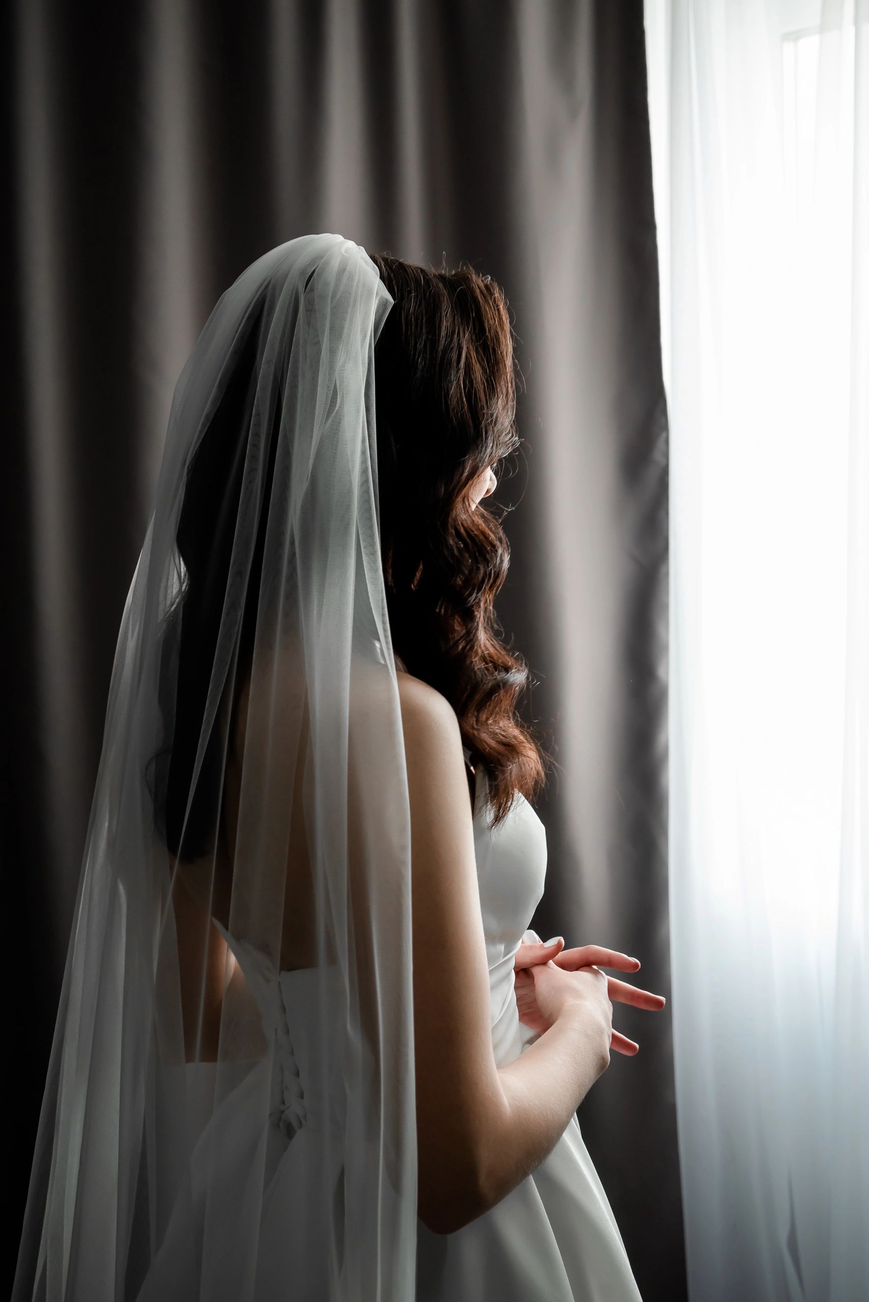 Bride in a veil gazing out a window before the ceremony